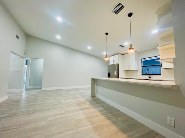 kitchen with white cabinetry, light hardwood / wood-style flooring, decorative light fixtures, sink, and stainless steel fridge with ice dispenser