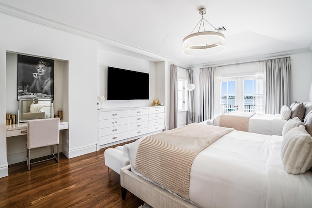 bedroom featuring ornamental molding, built in desk, dark hardwood / wood-style flooring, and french doors