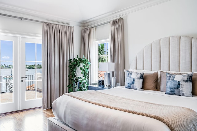 bedroom featuring french doors, a water view, crown molding, access to outside, and hardwood / wood-style floors