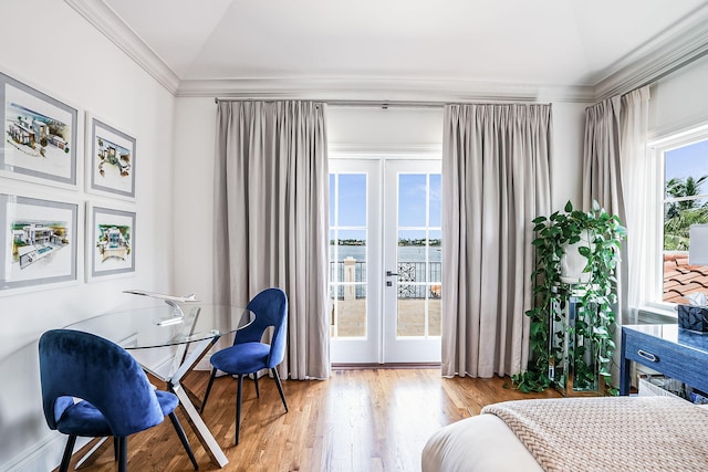 bedroom with crown molding, a water view, light hardwood / wood-style floors, and french doors