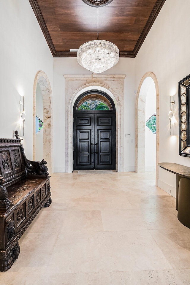 entrance foyer featuring crown molding, wooden ceiling, and a chandelier