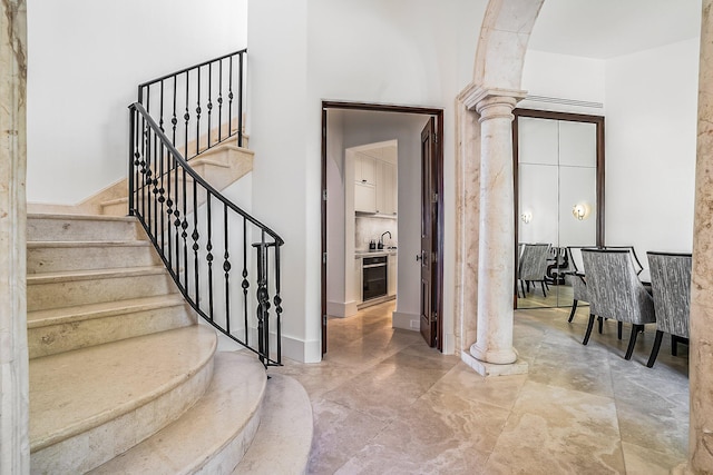 stairway with wine cooler, sink, and ornate columns