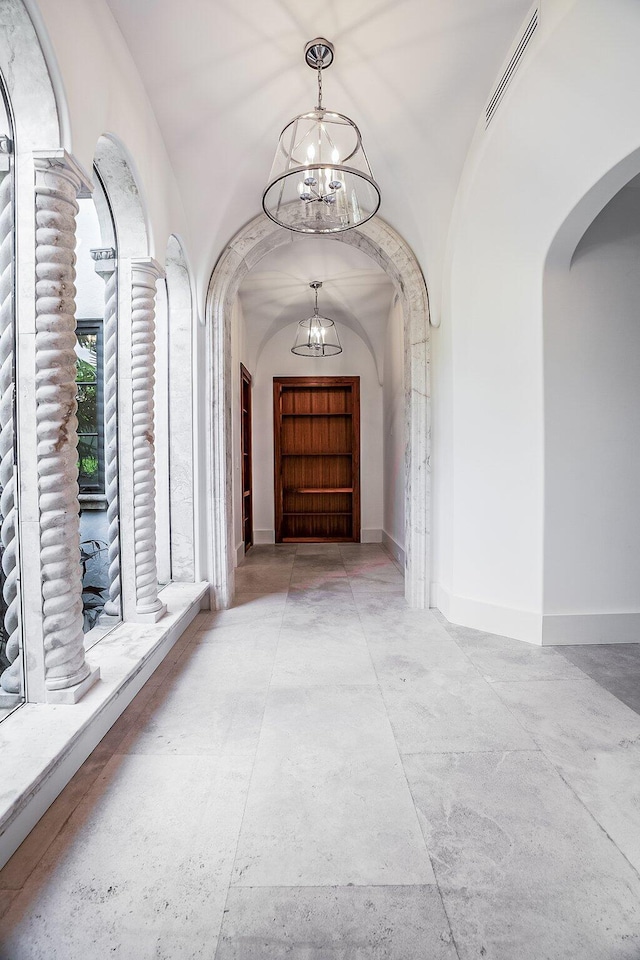 hall with an inviting chandelier and vaulted ceiling