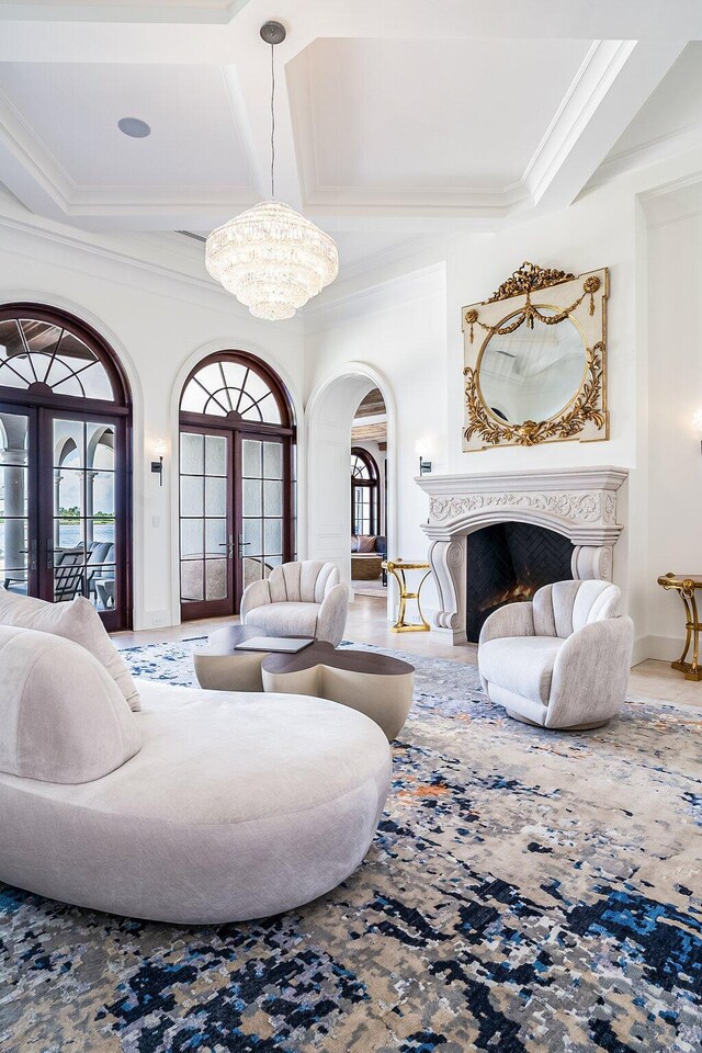 living room with crown molding, coffered ceiling, a chandelier, and french doors