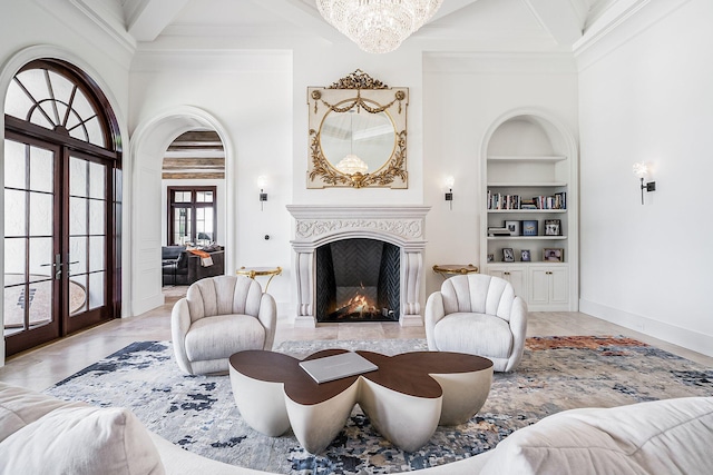 living room featuring french doors, ornamental molding, built in features, a notable chandelier, and beamed ceiling