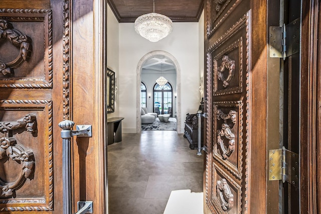 foyer entrance with crown molding and a chandelier