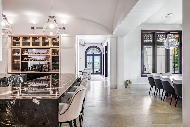 bar with dark stone countertops, pendant lighting, and concrete flooring