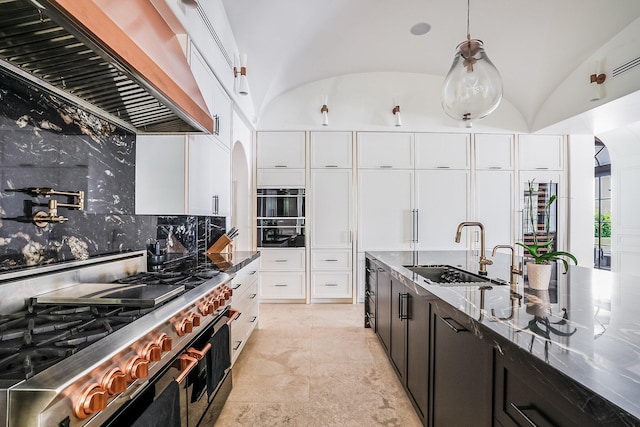 kitchen with lofted ceiling, sink, custom exhaust hood, white cabinetry, and range with two ovens