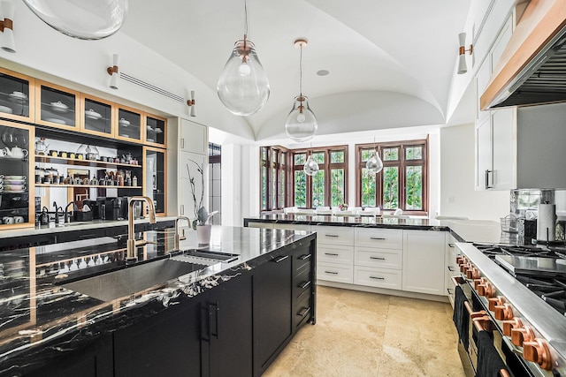 kitchen featuring premium range hood, lofted ceiling, stainless steel range, pendant lighting, and white cabinets