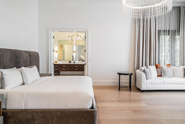 bedroom with connected bathroom, light hardwood / wood-style flooring, and a chandelier