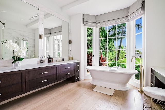 bathroom with vanity, a bathtub, hardwood / wood-style flooring, and a healthy amount of sunlight