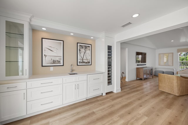 bar featuring sink, light hardwood / wood-style flooring, and white cabinets