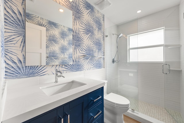 bathroom with vanity, toilet, and a shower with door