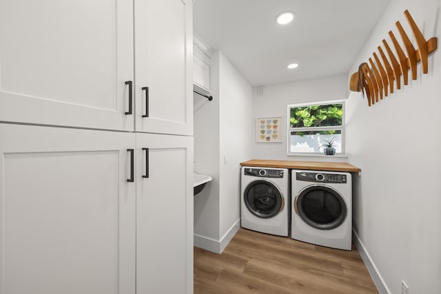 laundry area with cabinets, light hardwood / wood-style flooring, and washing machine and clothes dryer