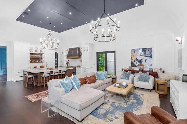 living room with a towering ceiling, sink, a notable chandelier, and dark hardwood / wood-style floors