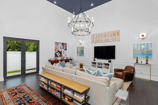 living room with a high ceiling, a notable chandelier, and dark hardwood / wood-style flooring