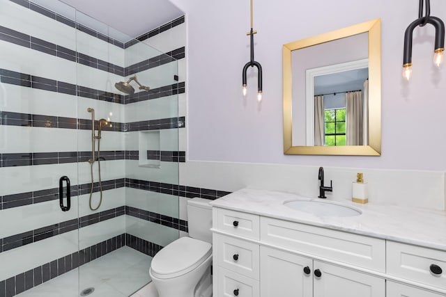 bathroom featuring vanity, toilet, tile walls, and a shower with door