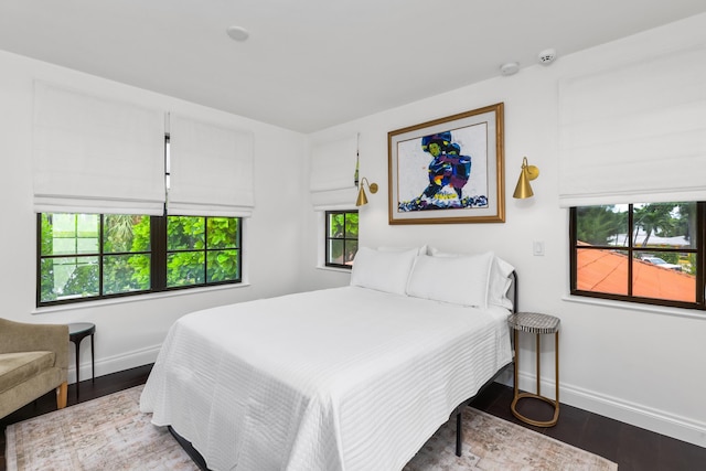 bedroom with multiple windows and dark hardwood / wood-style floors