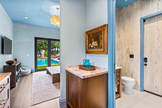 bathroom featuring vanity, toilet, wood walls, and hardwood / wood-style floors