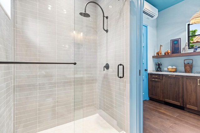 bathroom featuring vanity, wood-type flooring, an AC wall unit, and a shower with door