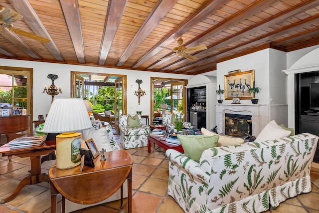 living room featuring beam ceiling, a premium fireplace, ceiling fan, and wooden ceiling