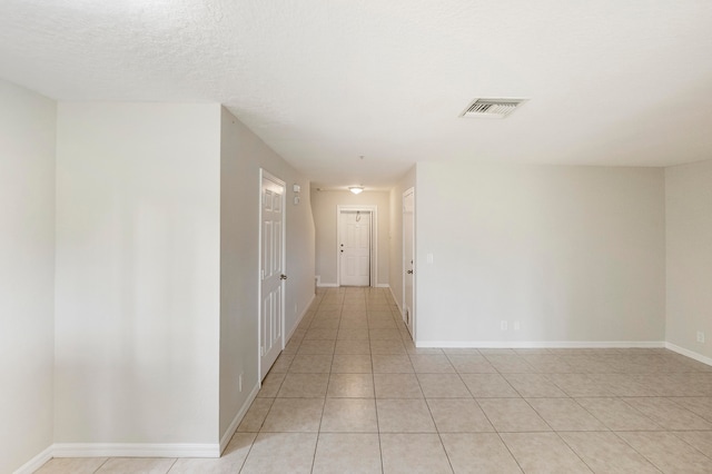 tiled empty room featuring a textured ceiling