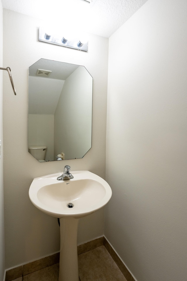 bathroom featuring a textured ceiling and tile patterned floors