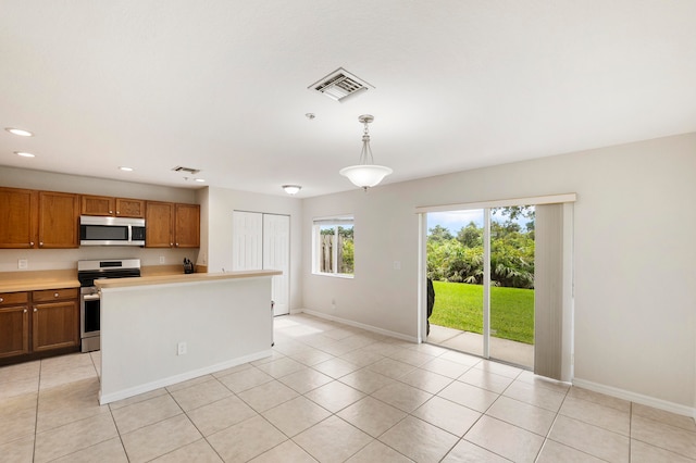 kitchen with hanging light fixtures, light tile patterned floors, and appliances with stainless steel finishes