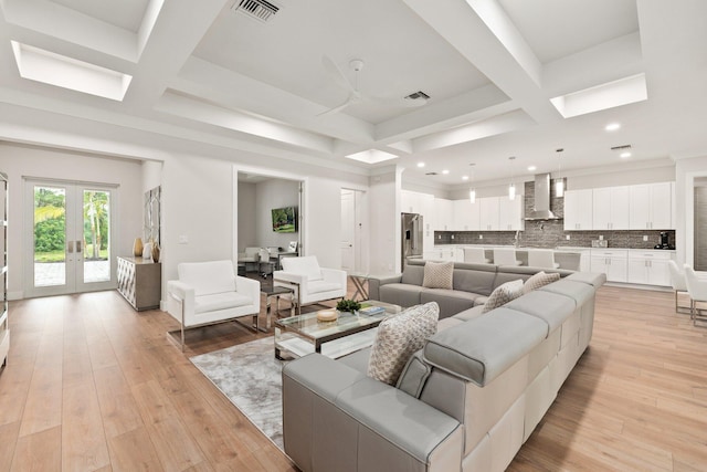 living room with light hardwood / wood-style flooring, coffered ceiling, and beamed ceiling