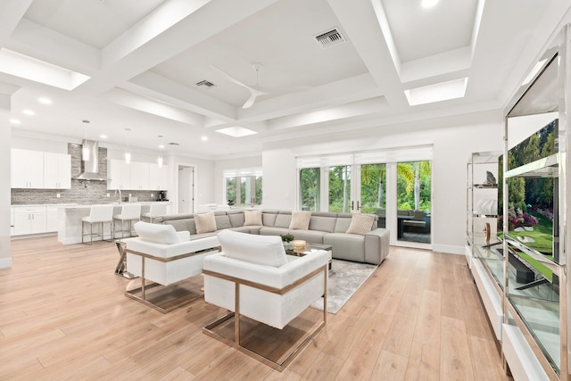 living room with beamed ceiling, coffered ceiling, and light hardwood / wood-style floors