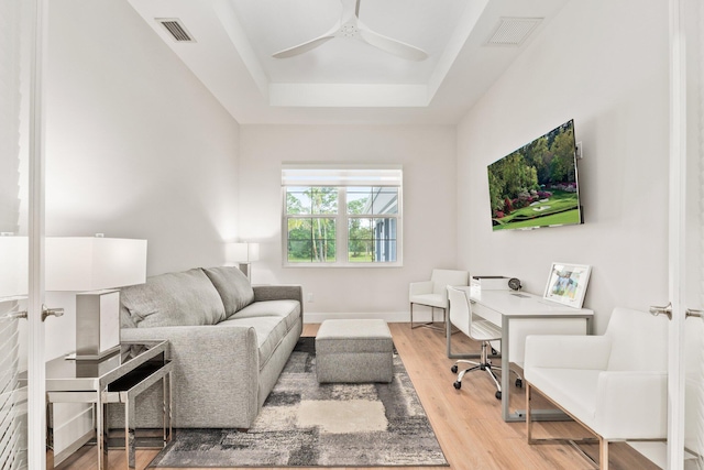 office area featuring a tray ceiling, french doors, light hardwood / wood-style flooring, and ceiling fan