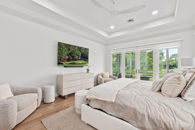 bedroom featuring french doors, a tray ceiling, ceiling fan, and light hardwood / wood-style flooring