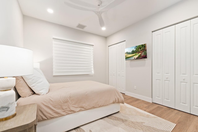 bedroom featuring ceiling fan, wood-type flooring, and multiple closets