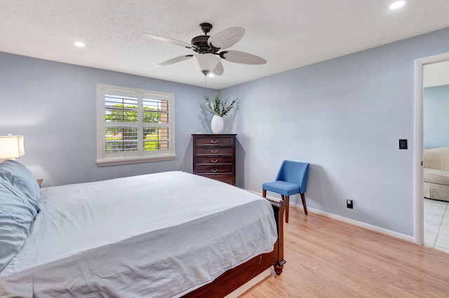 bedroom with a textured ceiling, ceiling fan, and light wood-type flooring