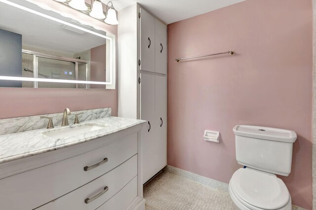 bathroom featuring a shower with door, vanity, toilet, and tile patterned floors