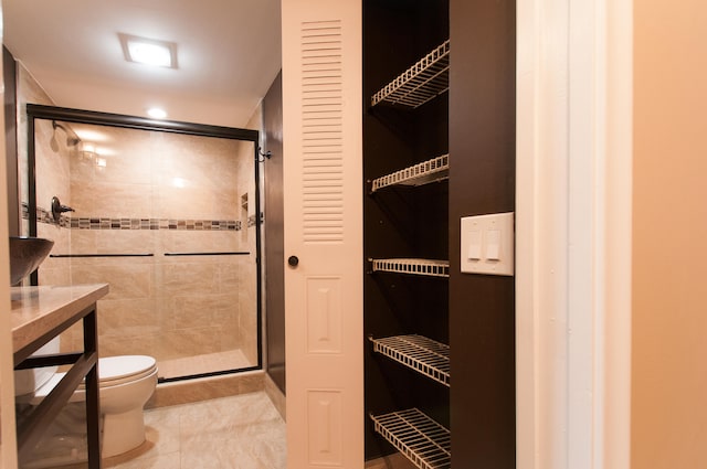 bathroom with a shower with door, toilet, and tile patterned flooring