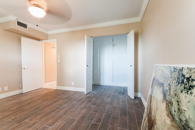 unfurnished bedroom featuring dark wood-type flooring, a closet, ceiling fan, and crown molding