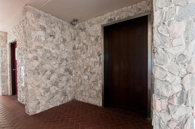 spare room with brick floor and a textured ceiling