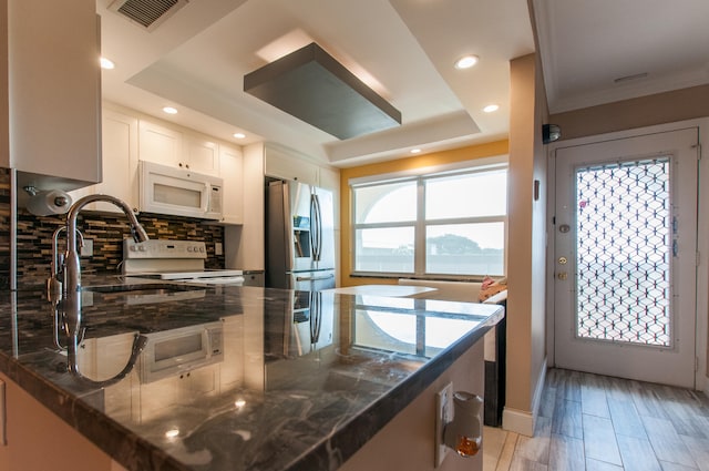 kitchen with a raised ceiling, light hardwood / wood-style flooring, stainless steel fridge with ice dispenser, tasteful backsplash, and white cabinets