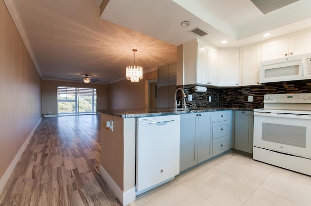 kitchen featuring crown molding, visible vents, a sink, white appliances, and a peninsula