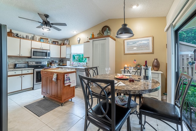 kitchen with ceiling fan, lofted ceiling, decorative light fixtures, white cabinetry, and appliances with stainless steel finishes