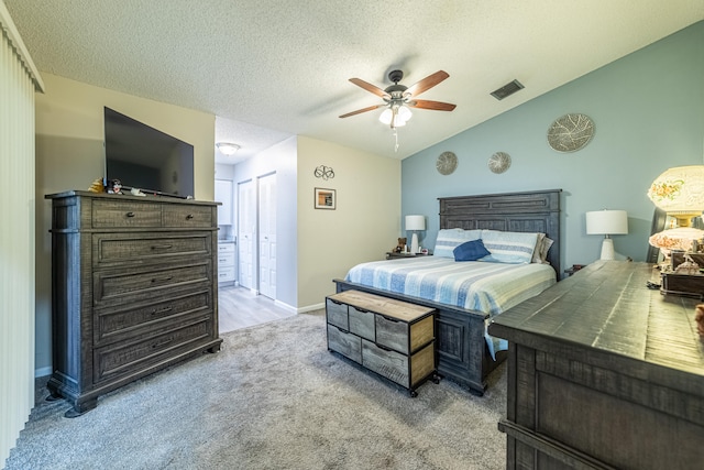 bedroom featuring light carpet, lofted ceiling, ceiling fan, and a textured ceiling