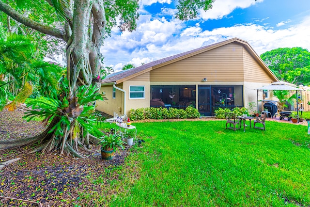 back of house featuring a yard and a sunroom