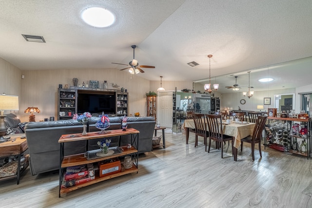 living room featuring ceiling fan, hardwood / wood-style flooring, vaulted ceiling, and a textured ceiling