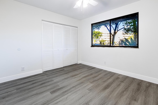 unfurnished bedroom with a closet, ceiling fan, and dark hardwood / wood-style flooring