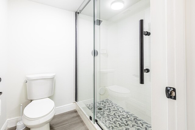 bathroom with wood-type flooring, an enclosed shower, and toilet