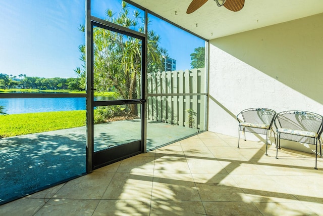 sunroom featuring ceiling fan and a water view