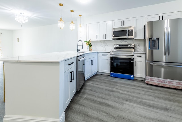 kitchen with stainless steel appliances, white cabinets, kitchen peninsula, and sink