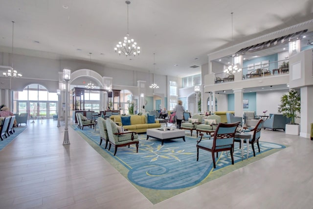 interior space with hardwood / wood-style floors, an inviting chandelier, a high ceiling, and ornate columns