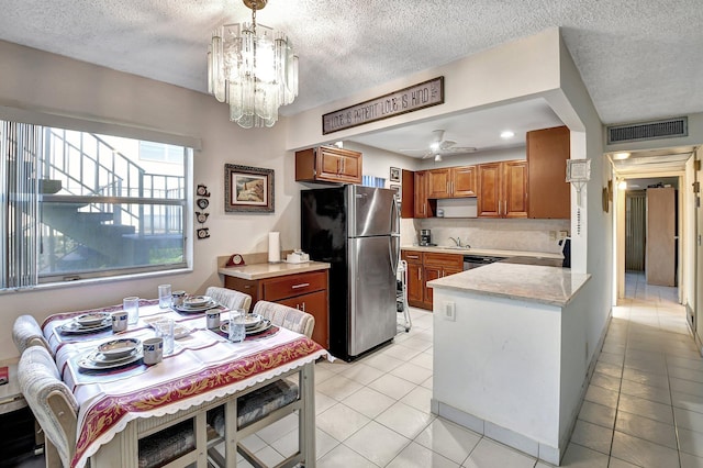 kitchen with ceiling fan with notable chandelier, a textured ceiling, light tile patterned floors, sink, and appliances with stainless steel finishes